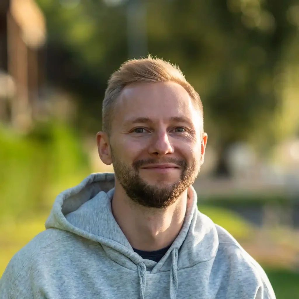 Willkommen auf hausbauplan.com 6 Mann mit Bart und grauem Hoodie im Freien bei Tageslicht vor unscharfem grünem Hintergrund